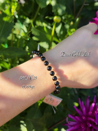 Black thread bracelet with gold details.