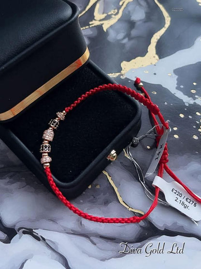 Red thread bracelet with gold details.